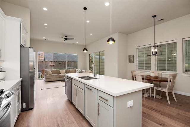 kitchen with pendant lighting, stainless steel appliances, sink, and white cabinets