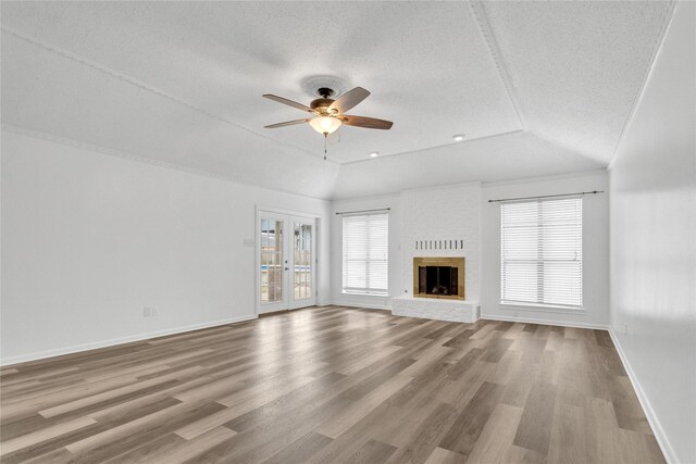 unfurnished living room featuring a brick fireplace, hardwood / wood-style floors, lofted ceiling, and ceiling fan