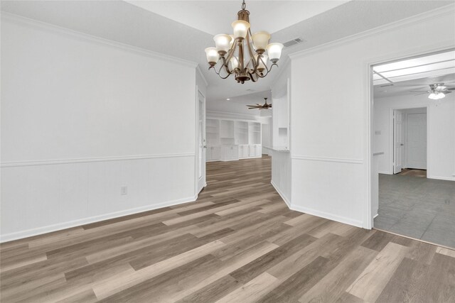 unfurnished dining area with hardwood / wood-style floors, ornamental molding, and ceiling fan with notable chandelier