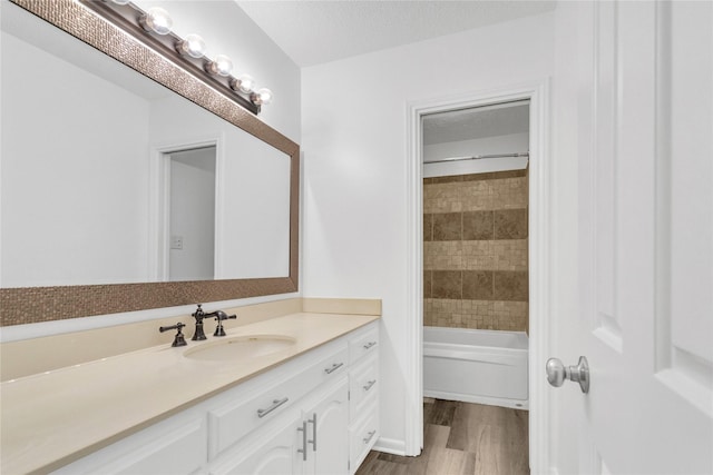 bathroom featuring vanity, hardwood / wood-style floors, tiled shower / bath, and a textured ceiling