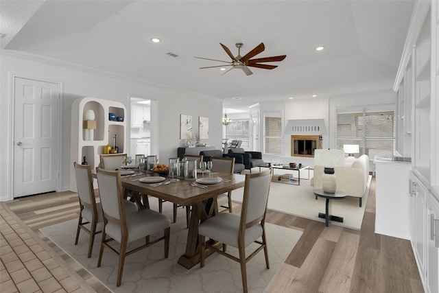 dining room with crown molding, a brick fireplace, a healthy amount of sunlight, and light hardwood / wood-style floors