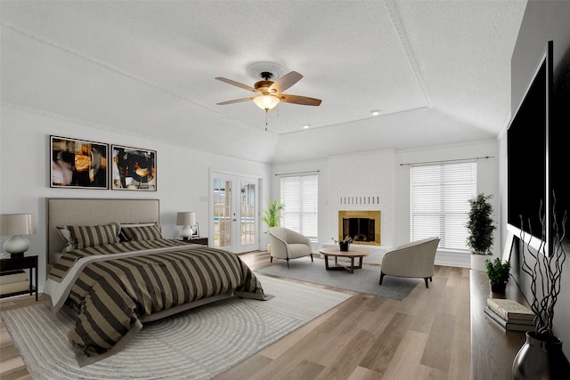 bedroom featuring french doors, multiple windows, a tray ceiling, and a brick fireplace