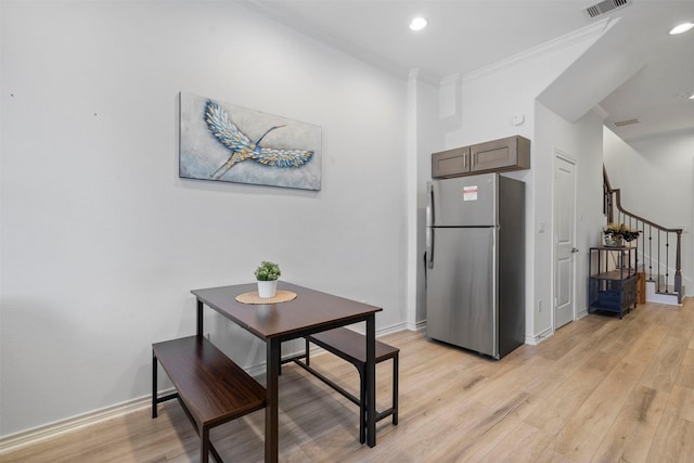 dining space featuring ornamental molding and light hardwood / wood-style floors