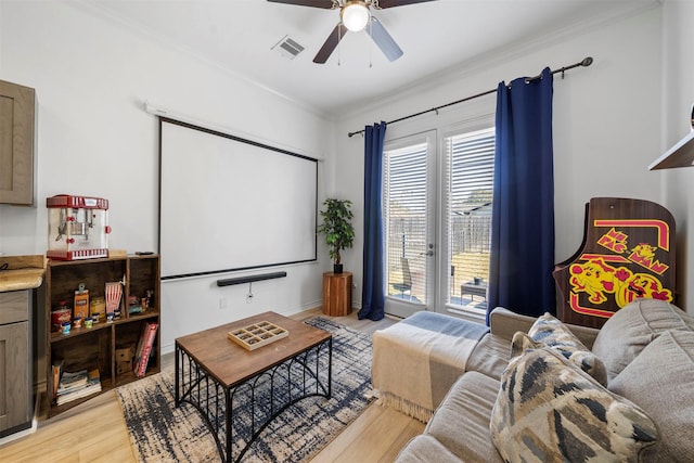 home theater room featuring ornamental molding, light hardwood / wood-style floors, and ceiling fan