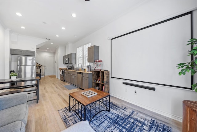 home theater room featuring ornamental molding, sink, and light hardwood / wood-style flooring