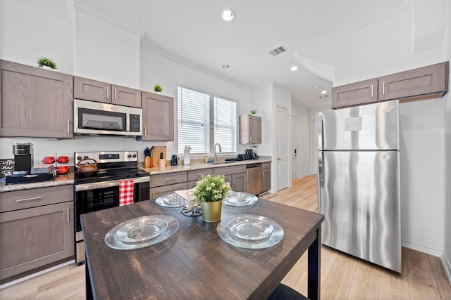 kitchen featuring stainless steel appliances, crown molding, sink, and light hardwood / wood-style flooring