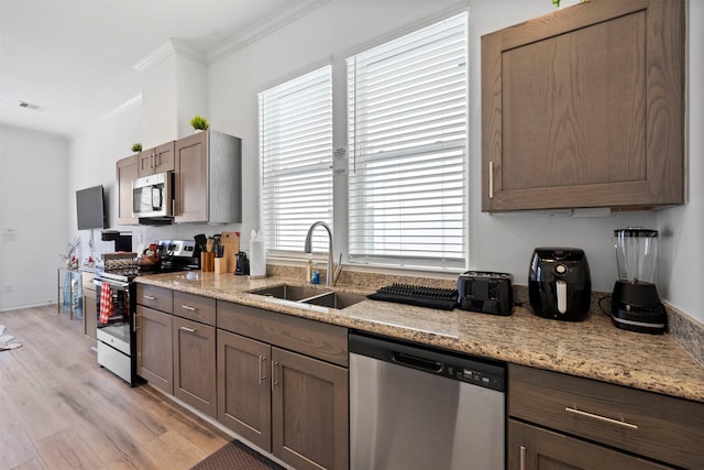 kitchen with stainless steel appliances, ornamental molding, plenty of natural light, and sink