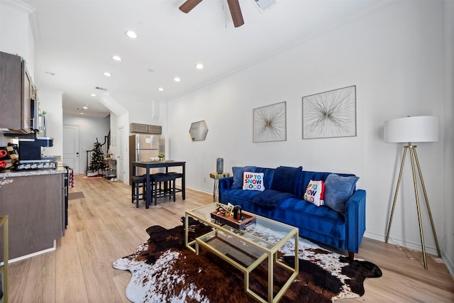 living room with crown molding, ceiling fan, and light hardwood / wood-style floors