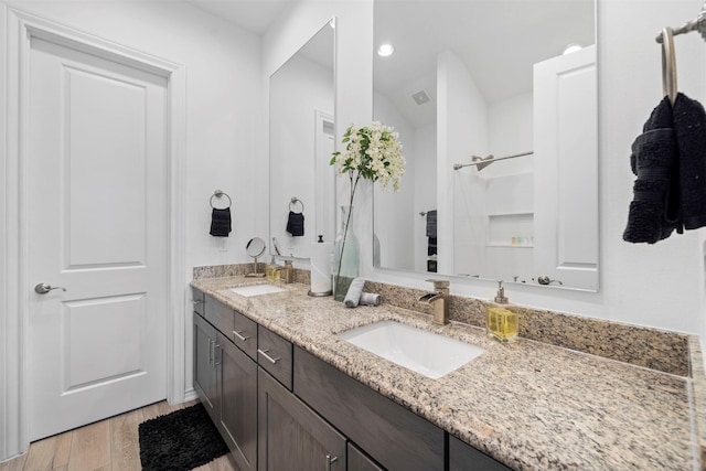 bathroom with wood-type flooring, vanity, and walk in shower