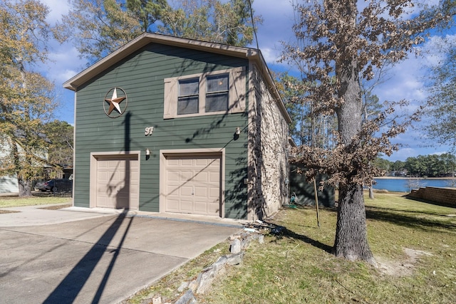 view of home's exterior with a yard, a garage, and a water view