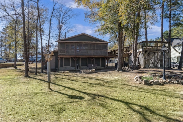 rear view of property featuring a sunroom, a lawn, a deck, and an outdoor fire pit