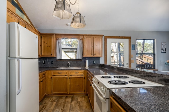 kitchen with pendant lighting, lofted ceiling, sink, dark wood-type flooring, and white appliances