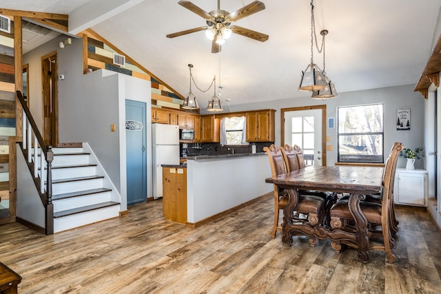 kitchen featuring vaulted ceiling with beams, hanging light fixtures, white fridge, light hardwood / wood-style floors, and backsplash