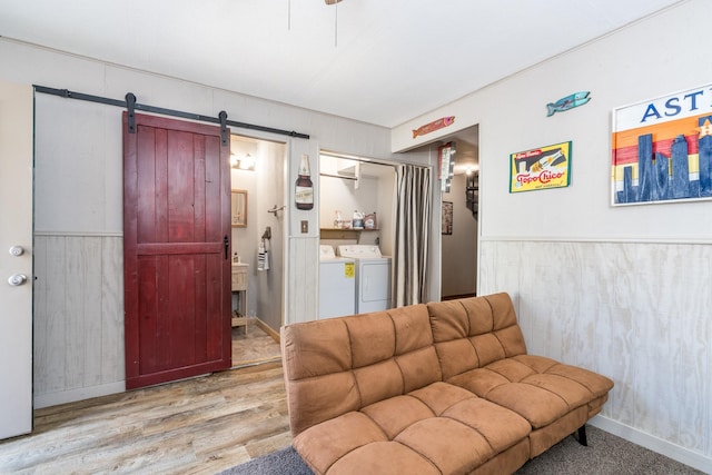 living room featuring separate washer and dryer, a barn door, and light wood-type flooring