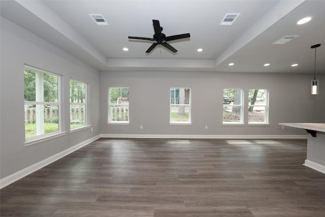 unfurnished living room with a raised ceiling, dark wood-type flooring, and ceiling fan