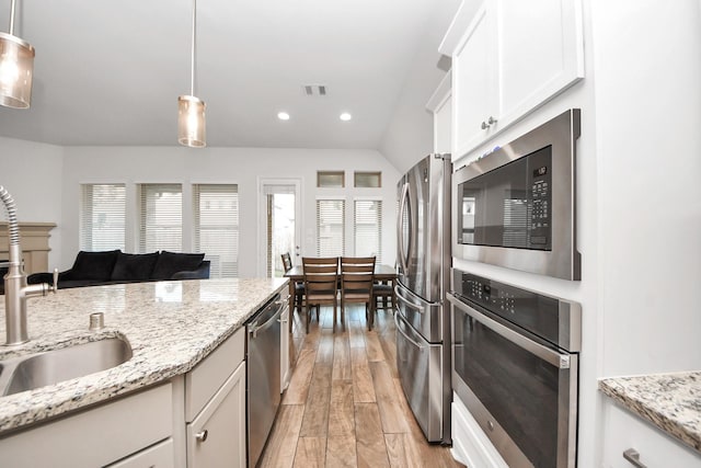 kitchen featuring light stone counters, decorative light fixtures, stainless steel appliances, light hardwood / wood-style floors, and white cabinets