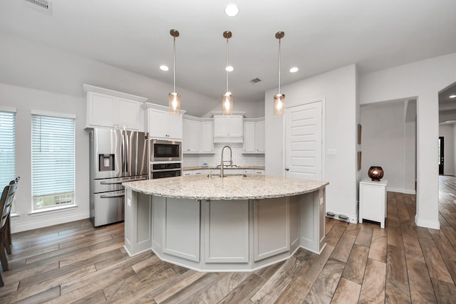 kitchen featuring decorative backsplash, wood finished floors, stainless steel appliances, white cabinetry, and a sink