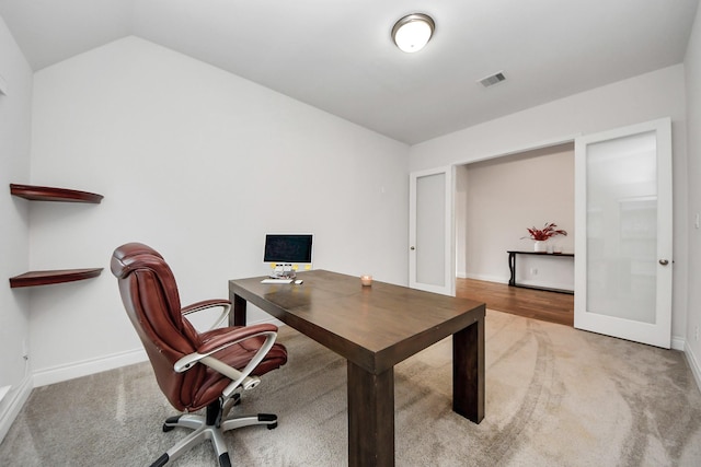 carpeted home office featuring french doors, visible vents, vaulted ceiling, and baseboards