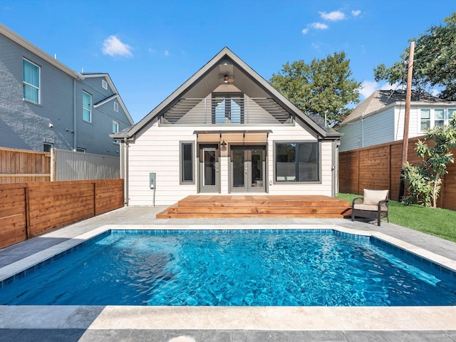 rear view of house featuring french doors and a fenced in pool