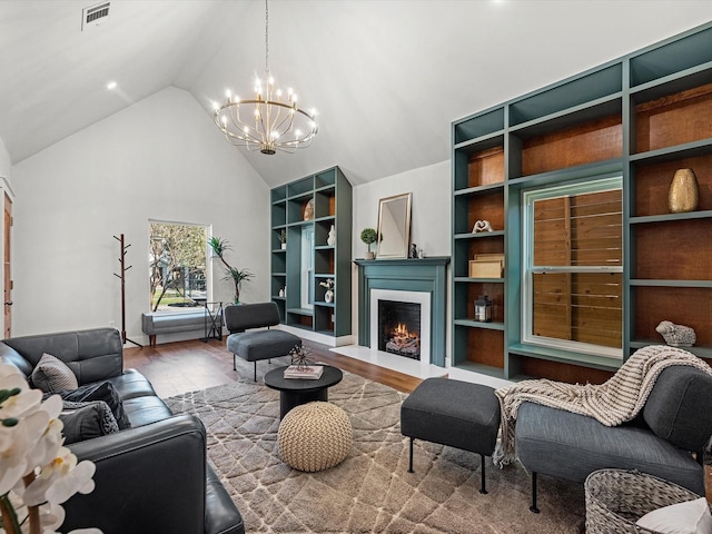 living room with hardwood / wood-style flooring, lofted ceiling, a chandelier, and built in shelves