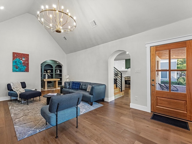 living room featuring hardwood / wood-style flooring, high vaulted ceiling, a chandelier, and built in shelves