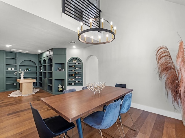 dining area featuring a notable chandelier, wood-type flooring, and built in features