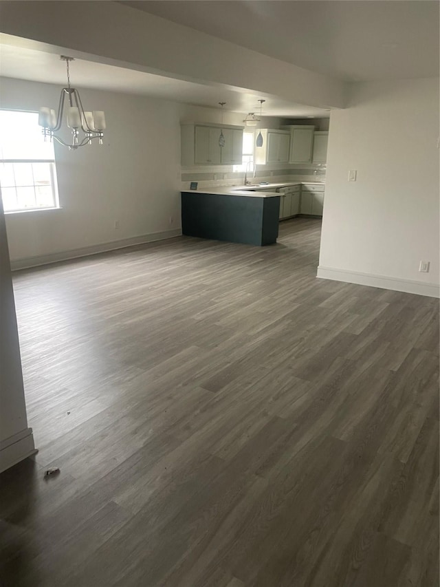 unfurnished living room with dark hardwood / wood-style floors, sink, and an inviting chandelier