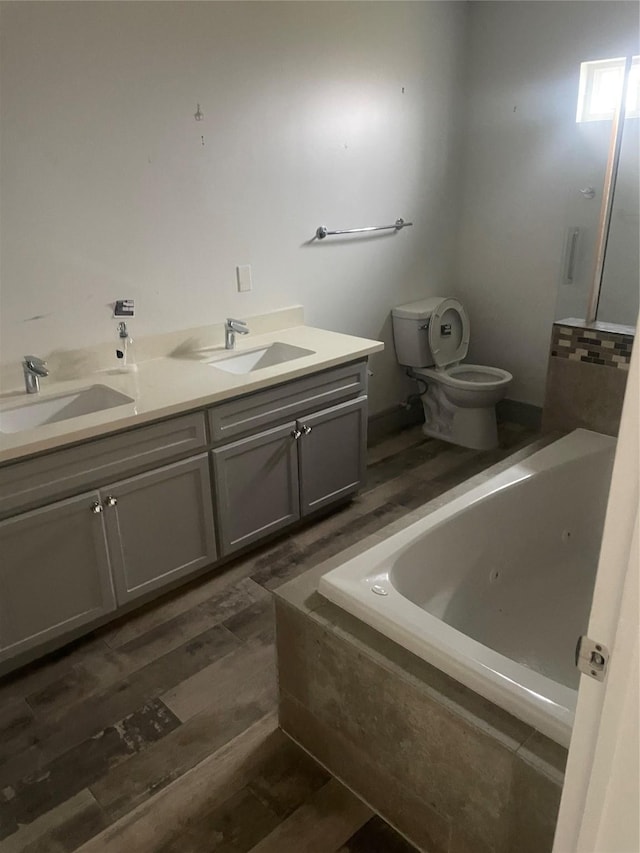 bathroom with vanity, toilet, and tiled bath