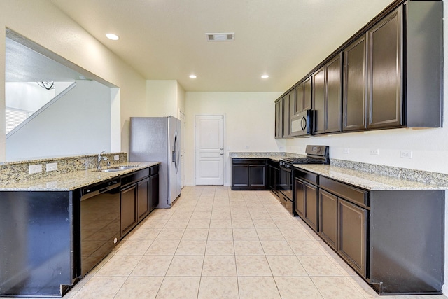 kitchen with light stone counters, sink, dark brown cabinets, and black appliances