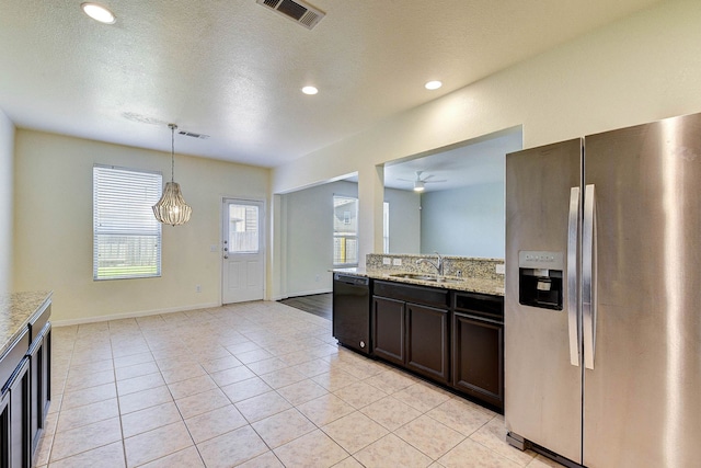 kitchen featuring sink, stainless steel fridge, black dishwasher, light stone countertops, and decorative light fixtures