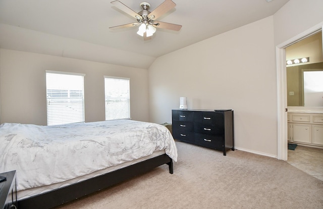 bedroom with vaulted ceiling, connected bathroom, light colored carpet, and ceiling fan