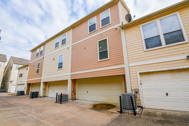 rear view of property with a garage and central AC unit