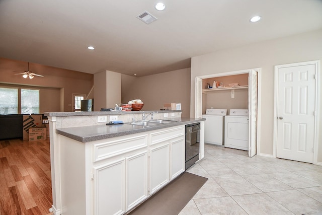 kitchen featuring white cabinetry, dishwasher, sink, light tile patterned floors, and washing machine and clothes dryer