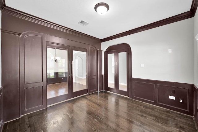 unfurnished room featuring french doors, crown molding, dark wood-type flooring, and a notable chandelier