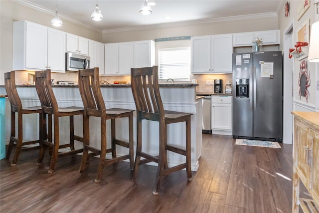 kitchen with stainless steel appliances, white cabinetry, and a breakfast bar