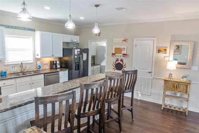 kitchen featuring pendant lighting, white cabinetry, sink, a breakfast bar area, and stainless steel appliances