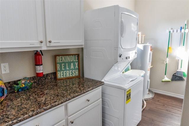 washroom featuring stacked washer and dryer, wood-type flooring, cabinets, and electric water heater