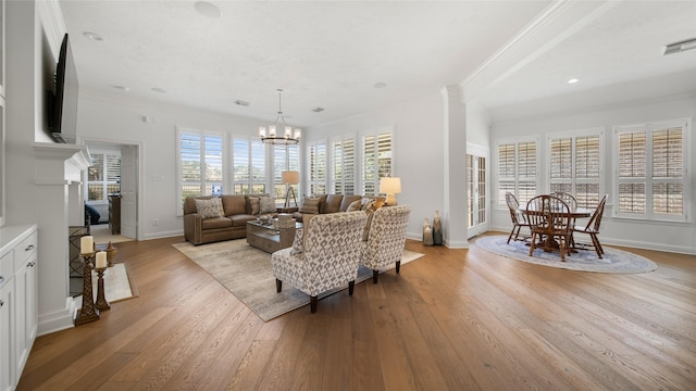 living room featuring crown molding, a healthy amount of sunlight, and an inviting chandelier