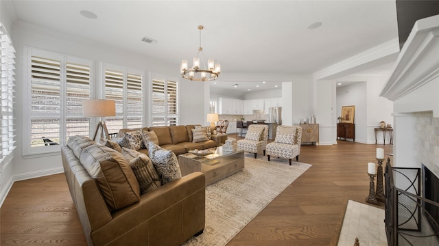 living room with a tile fireplace, dark hardwood / wood-style floors, a notable chandelier, and crown molding