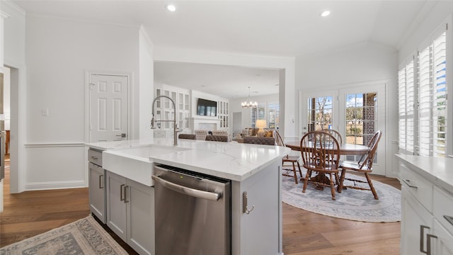 kitchen featuring stainless steel dishwasher, ornamental molding, sink, and an island with sink