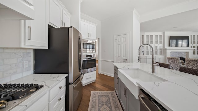 kitchen with white cabinetry, appliances with stainless steel finishes, light stone countertops, and sink