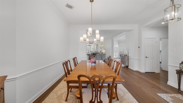 dining area featuring an inviting chandelier, crown molding, and dark wood-type flooring