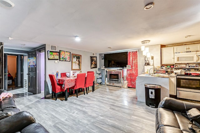 dining space with a brick fireplace, light wood-type flooring, and sink