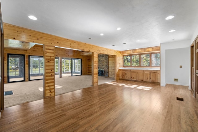 unfurnished living room with a stone fireplace and light wood-type flooring