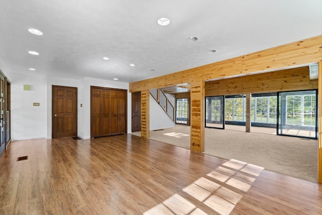 unfurnished living room featuring light carpet and wood walls