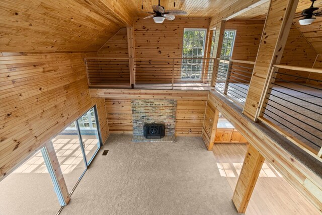 unfurnished living room featuring wood walls, lofted ceiling, light carpet, and wooden ceiling