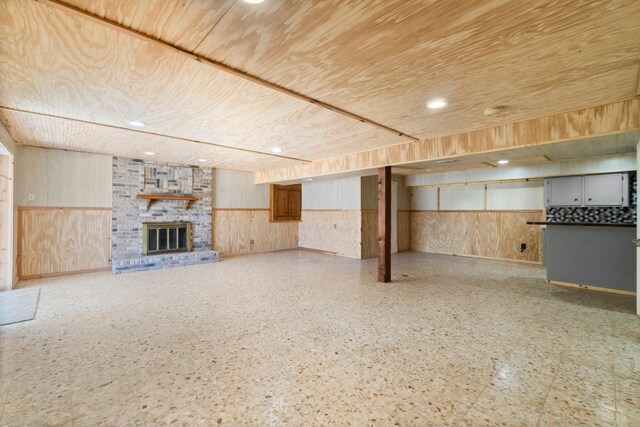 basement with wooden walls, a brick fireplace, and wooden ceiling