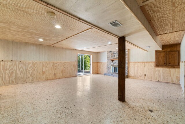 basement with a fireplace and wooden walls