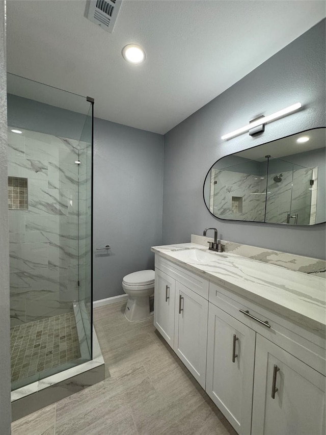 bathroom featuring vanity, toilet, and a shower with shower door