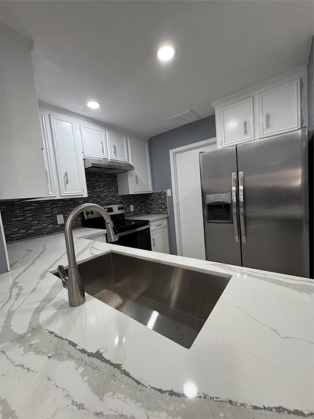 kitchen with sink, appliances with stainless steel finishes, white cabinetry, tasteful backsplash, and light stone countertops